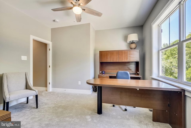 home office with a ceiling fan, light colored carpet, and baseboards