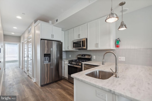 kitchen featuring white cabinetry, decorative backsplash, light stone countertops, appliances with stainless steel finishes, and dark wood-type flooring