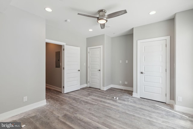 unfurnished bedroom with hardwood / wood-style flooring, electric panel, and ceiling fan