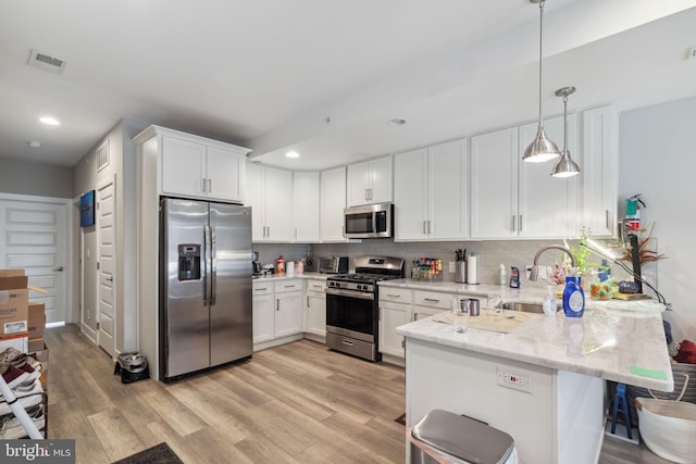 kitchen featuring stainless steel appliances, light hardwood / wood-style floors, sink, and kitchen peninsula