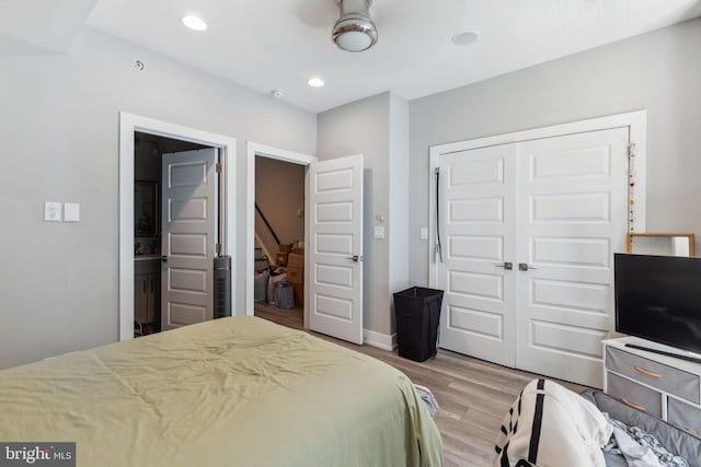 bedroom with ceiling fan, connected bathroom, a closet, and hardwood / wood-style flooring