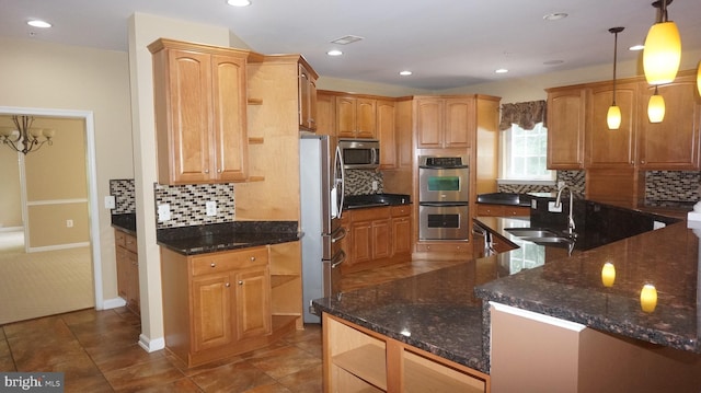 kitchen featuring sink, hanging light fixtures, dark stone countertops, tasteful backsplash, and stainless steel appliances