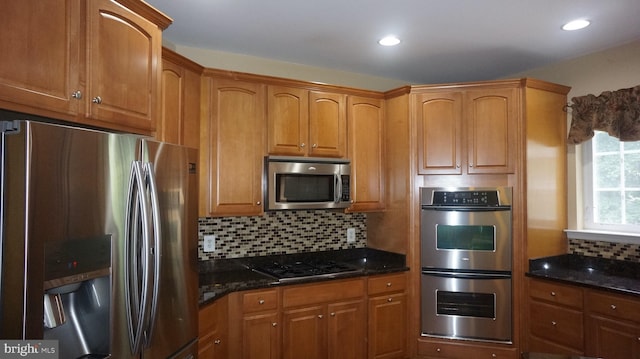 kitchen featuring decorative backsplash, dark stone countertops, and appliances with stainless steel finishes