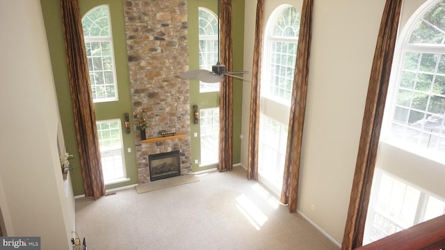 unfurnished living room featuring light carpet, a fireplace, and ceiling fan