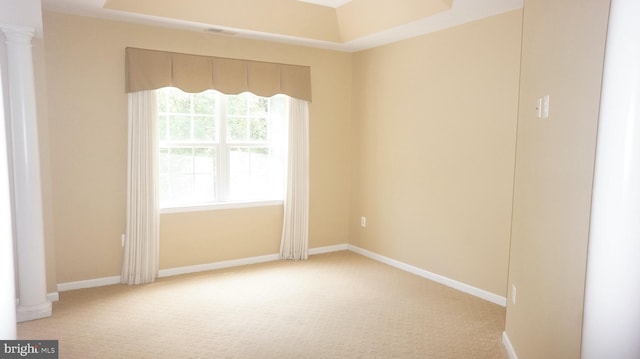 carpeted spare room featuring decorative columns and a tray ceiling