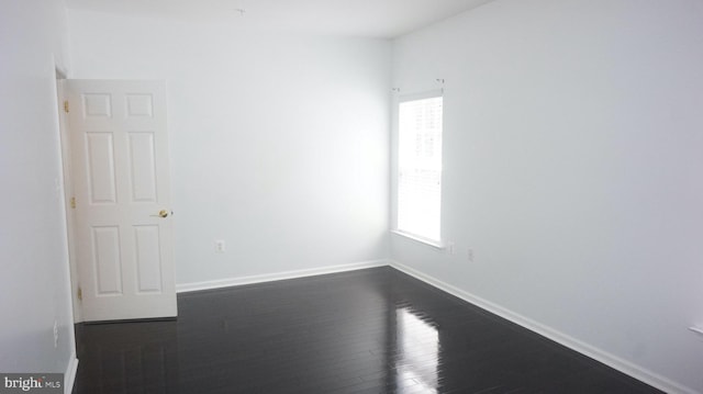 empty room featuring a healthy amount of sunlight and dark hardwood / wood-style flooring