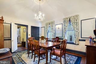 dining room with a notable chandelier, hardwood / wood-style flooring, and high vaulted ceiling