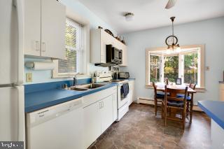 kitchen with stainless steel appliances, white cabinets, sink, dark tile patterned flooring, and decorative light fixtures