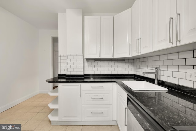 kitchen featuring dark stone counters, white cabinetry, decorative backsplash, sink, and light tile patterned floors