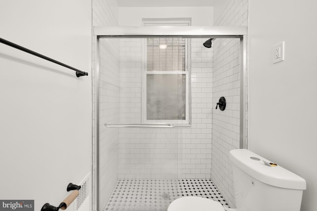 bathroom with a shower with shower door and toilet