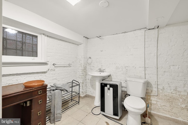 bathroom with brick wall, tile patterned floors, and toilet