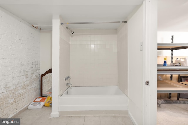 bathroom featuring brick wall, tiled shower / bath combo, and tile patterned floors