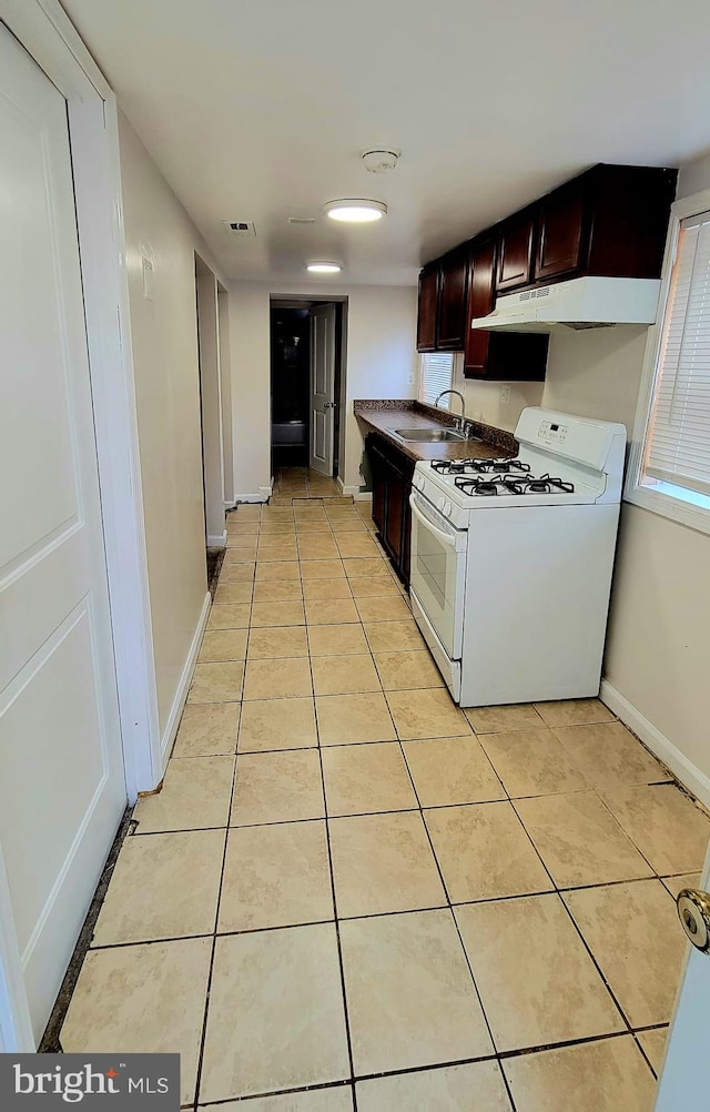 kitchen with light tile patterned flooring, sink, gas range gas stove, and dark brown cabinetry