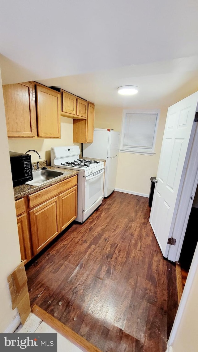 kitchen with white appliances, dark wood-type flooring, and sink