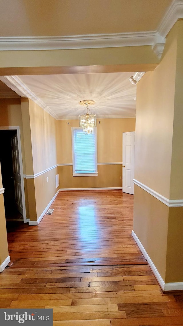 unfurnished room featuring an inviting chandelier, wood-type flooring, vaulted ceiling, and ornamental molding