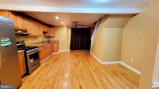 kitchen featuring light wood-type flooring, stainless steel appliances, light stone counters, ceiling fan, and sink