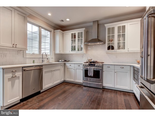 kitchen with sink, wall chimney exhaust hood, dark hardwood / wood-style floors, high quality appliances, and white cabinets