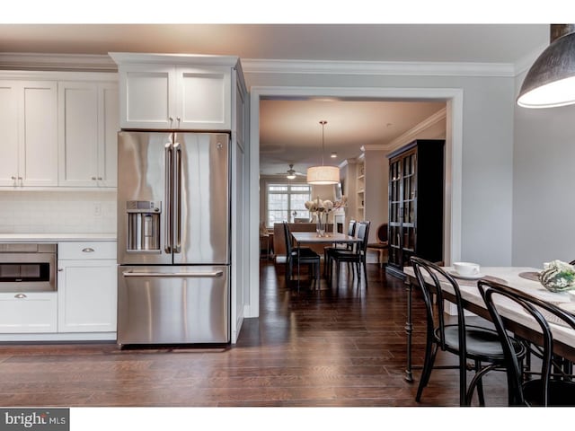 kitchen featuring decorative backsplash, white cabinetry, hanging light fixtures, and appliances with stainless steel finishes