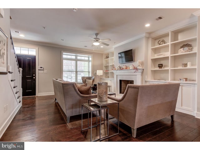 living room with crown molding, built in features, ceiling fan, and dark hardwood / wood-style floors