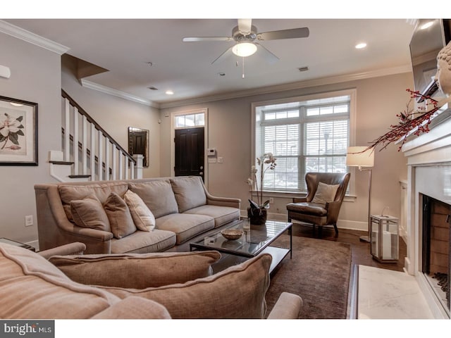 living room with hardwood / wood-style floors, ceiling fan, crown molding, and a premium fireplace