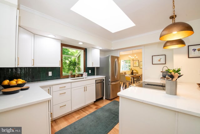 kitchen with sink, white cabinets, stainless steel appliances, and decorative light fixtures