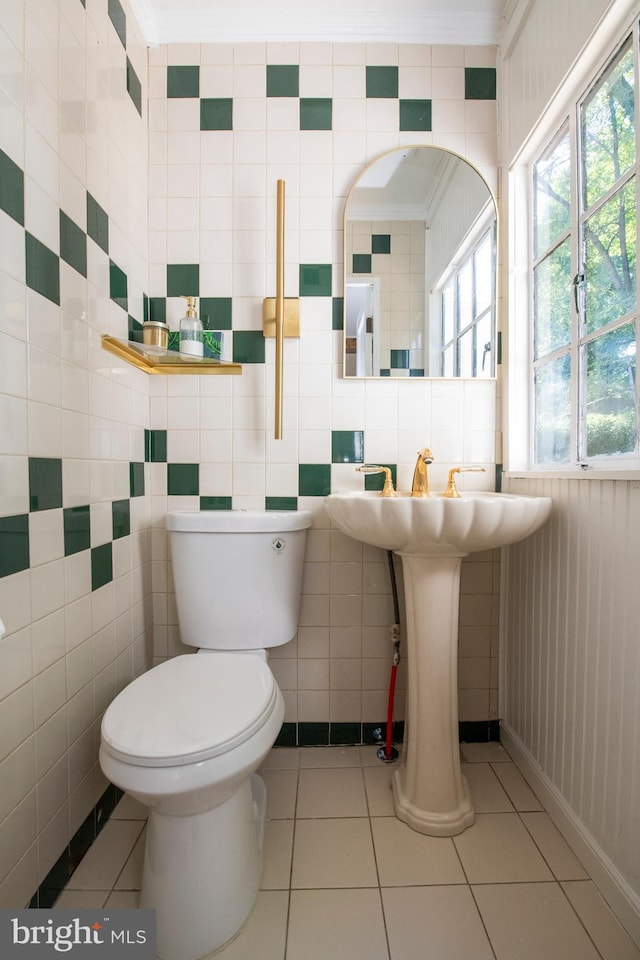 bathroom with tile patterned flooring, toilet, ornamental molding, and tile walls