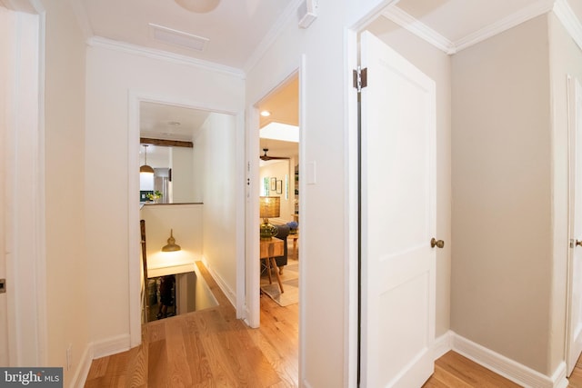 corridor with light hardwood / wood-style flooring and ornamental molding