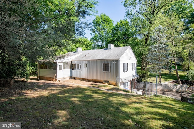 rear view of house featuring a lawn and a sunroom