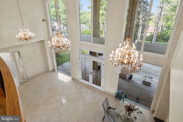 entrance foyer with a towering ceiling, french doors, and a chandelier