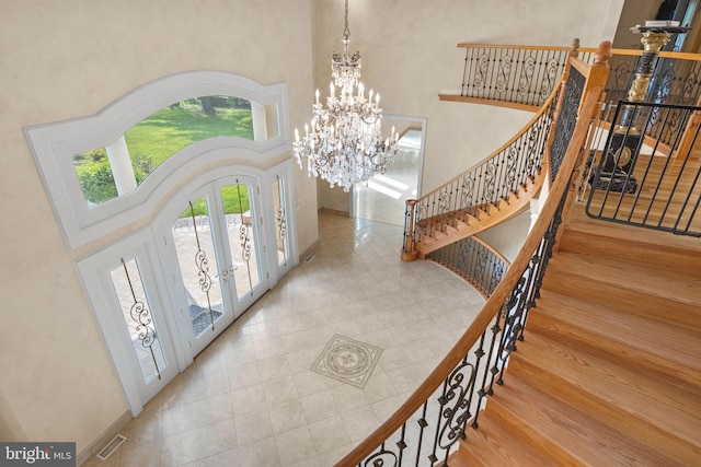 foyer entrance featuring french doors, an inviting chandelier, and a high ceiling