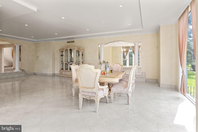 dining area featuring a raised ceiling, crown molding, and decorative columns