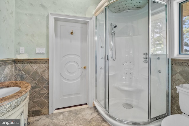 bathroom with vanity, toilet, tile walls, and a shower with shower door