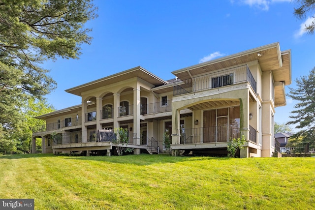 back of property with a lawn and a balcony