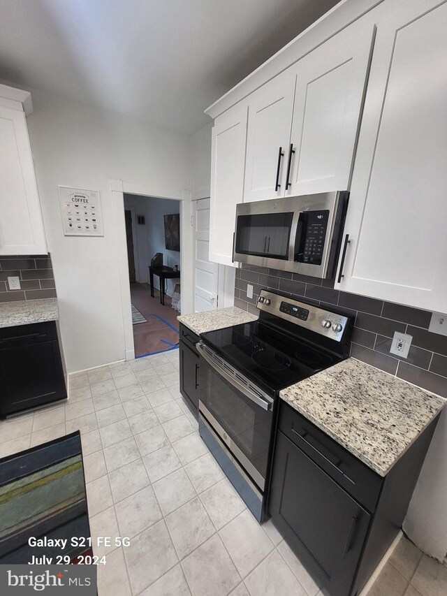 kitchen with light tile patterned flooring, appliances with stainless steel finishes, decorative backsplash, and white cabinets