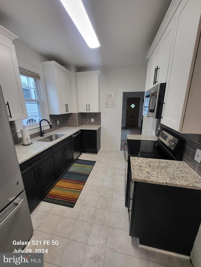 kitchen with white cabinets, appliances with stainless steel finishes, tasteful backsplash, sink, and light tile patterned floors