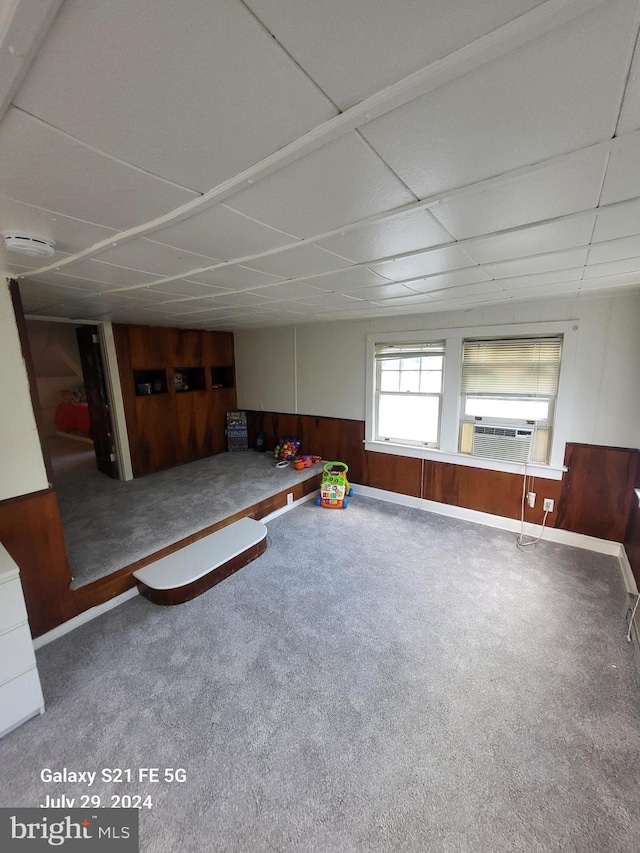 recreation room featuring cooling unit, a paneled ceiling, wooden walls, and carpet flooring