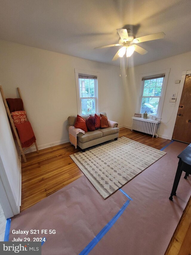 living room featuring hardwood / wood-style flooring, a wealth of natural light, radiator heating unit, and ceiling fan