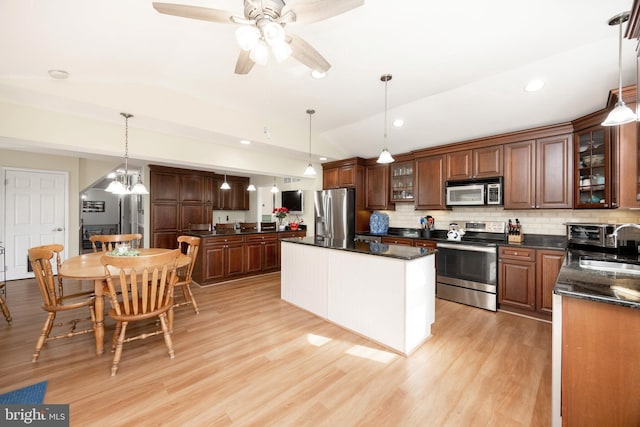 kitchen with lofted ceiling, appliances with stainless steel finishes, light wood-style floors, and a center island