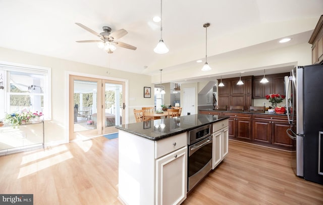 kitchen featuring stainless steel appliances, decorative light fixtures, a kitchen island, and light wood finished floors