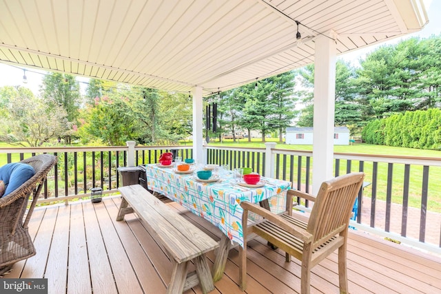 wooden terrace featuring a yard, a shed, outdoor dining area, and an outdoor structure