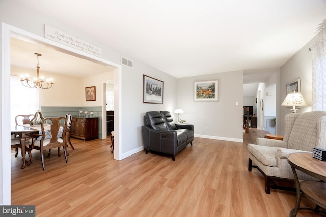 sitting room with light wood finished floors, baseboards, visible vents, and an inviting chandelier