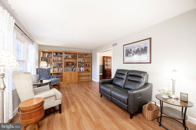 living area with light wood-style floors, visible vents, and baseboards