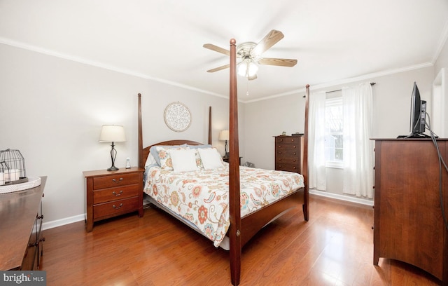 bedroom with baseboards, ceiling fan, wood finished floors, and crown molding