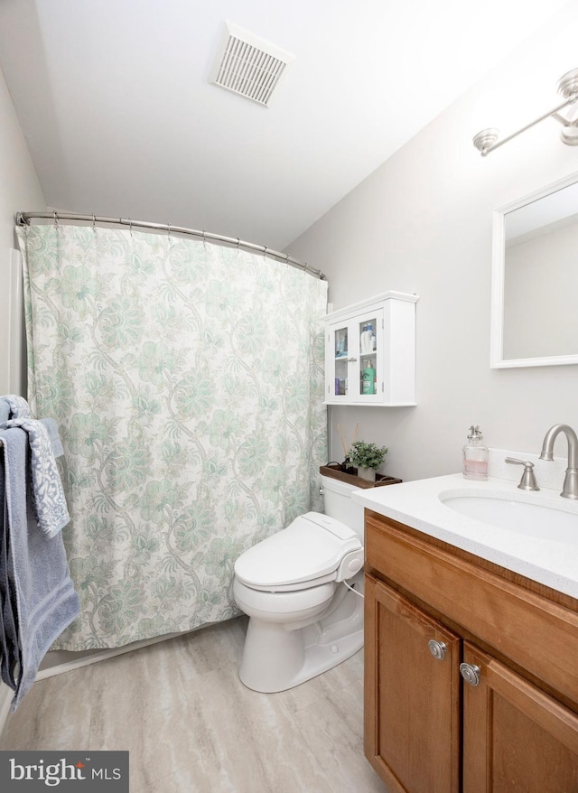 bathroom with toilet, visible vents, wood finished floors, and vanity