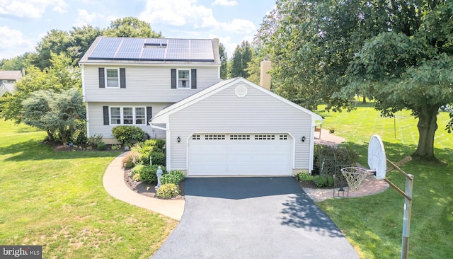 view of front of home with aphalt driveway, a chimney, solar panels, an attached garage, and a front yard