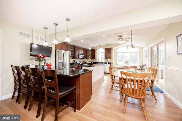 kitchen featuring a peninsula, light wood finished floors, visible vents, and stainless steel appliances