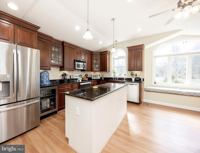 kitchen featuring lofted ceiling, beverage cooler, stainless steel appliances, light wood-style floors, and decorative backsplash