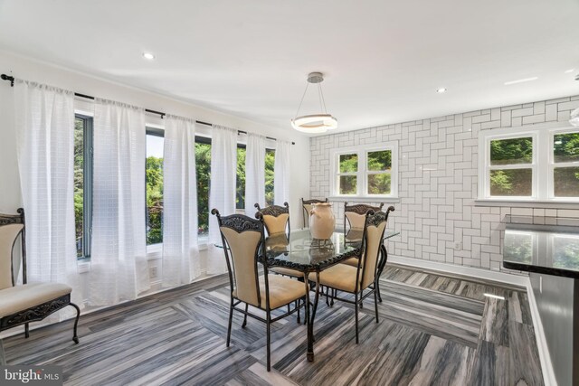 kitchen featuring appliances with stainless steel finishes, dark stone counters, white cabinets, hanging light fixtures, and light wood-type flooring