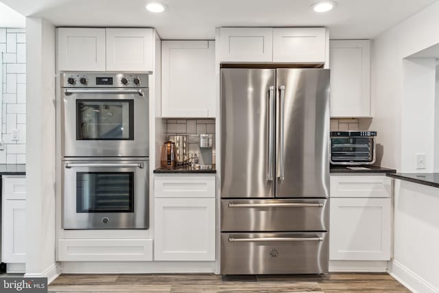 kitchen featuring white cabinets, tasteful backsplash, and wall chimney range hood