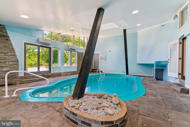 view of pool with a wall mounted AC and a skylight